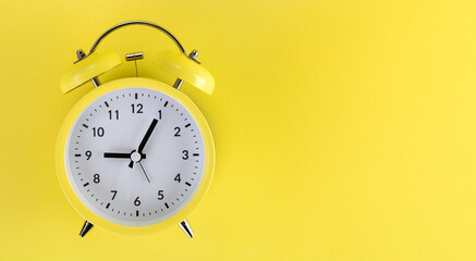 Yellow alarm clock on a colored yellow background. Top view. Copy space. Monochrome. Minimalism. Concept of time, planning.