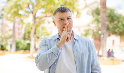 handsome man looking serious and cross with finger pressed to lips demanding silence or quiet, keeping a secret