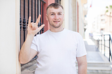 handsome man feeling happy, fun, confident, positive and rebellious, making rock or heavy metal sign with hand