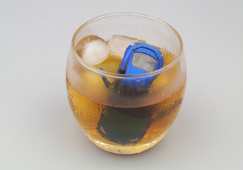 Drunk driving concept. Car drowned in glass with alcohol on gray background.