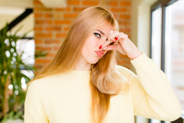 young pretty woman feeling disgusted, holding nose to avoid smelling a foul and unpleasant stench. home interior