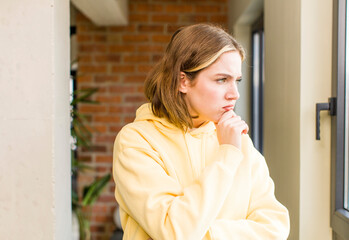 pretty caucasian woman feeling confused or doubting, concentrating on an idea, thinking hard, looking to copy space on side. home interior concept