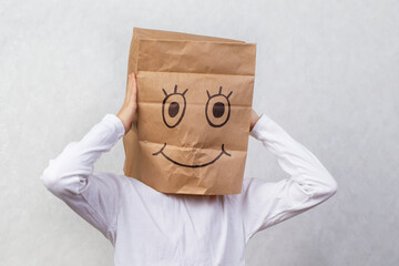 A child with cardboard boxes on his head, on which a smile is drawn with a marker. The concept of...
