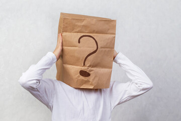 Anonymous man on a gray background with a cardboard box on his head with a drawn question mark. Problems and solutions. Getting answers.