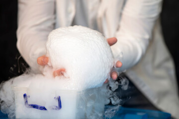 Laboratory chemistry experiment with foam and steaming.Laboratory chemical experiment with foam and steam. Hands holding foam.