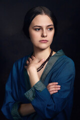 Portrait of pretty young girl in elegant retro clothing over dark vintage background. Concept of...