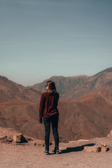 Woman captivated by the Atlas landscape, her gaze embracing the majestic peaks and tranquil valleys with a sense of awe and wonder.