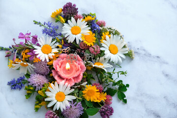 candle with pentacle amulet and colorful flowers on abstract marble background close up. esoteric...