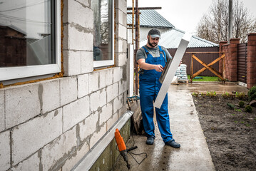 Worker holds adhesive styrofoam to the wall. Building insulation saves energy. Facade renovation