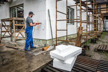 Worker makes building insulation saves energy with styrofoam. Facade renovation - obrazy, fototapety, plakaty