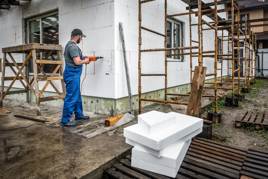 Worker makes building insulation saves energy with styrofoam. Facade renovation