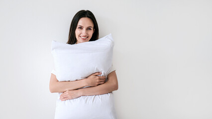 Young smiling woman looking at camera, embracing pillow with memory foam