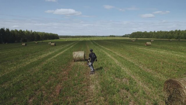 2. Aerial photography of electric skateboarding, electric skateboarding, skateboarder rides on a field with haystacks, electric longboard evolve