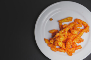 close-up orange crispy snack on white plate with dark background