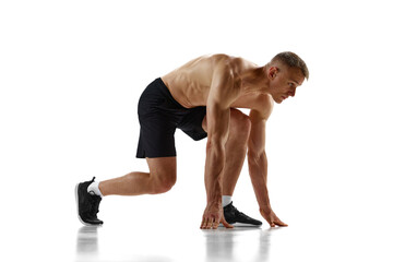 Obraz premium Ready, steady, go. Muscular man, professional athlete, runner standing in position to start running against white studio background