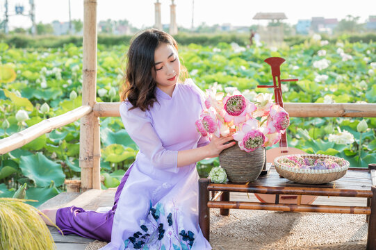Vietnamese woman wearing traditional dress (ao dai) in a lotus flower pond