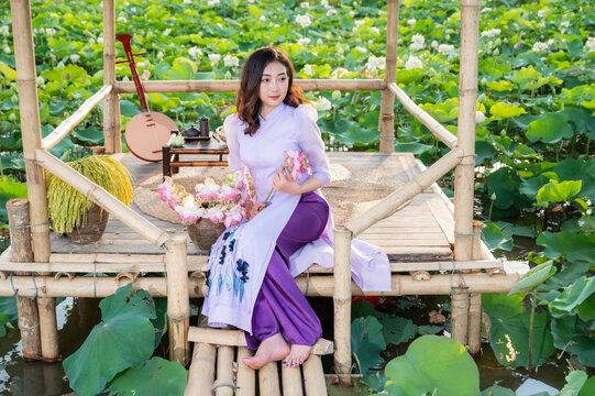Vietnamese woman wearing traditional dress (ao dai) in a lotus flower pond