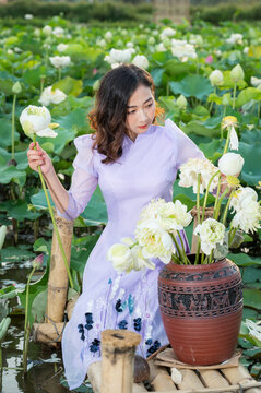Vietnamese woman wearing traditional dress (ao dai) in a lotus flower pond