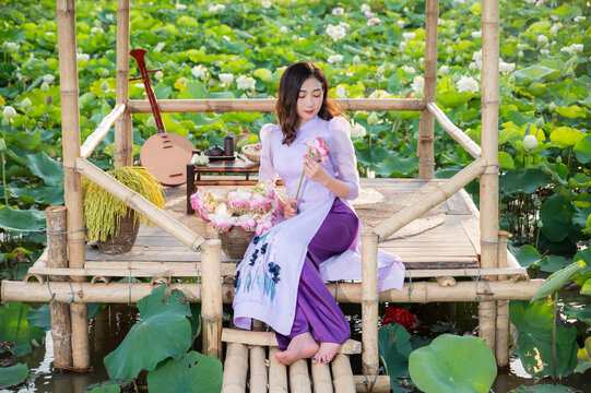 Vietnamese woman wearing traditional dress (ao dai) in a lotus flower pond
