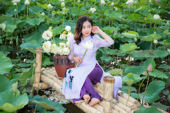 Vietnamese woman wearing traditional dress (ao dai) in a lotus flower pond