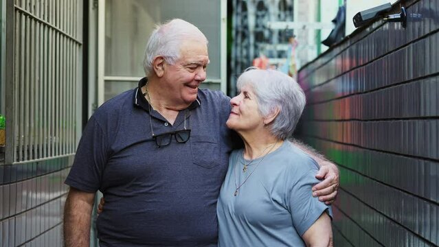 Happy senior couple smiling at camera standing in casual residence outside. Elderly husband and wife at old age portrait