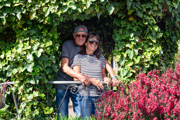 Happy senior family couple  in denim and sunglasses hugging in travel vacation relaxing in the garden enjoying beauty in nature