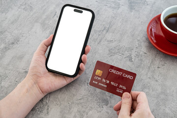 Online shopping in internet concept. Woman using credit card and blank smartphone on  Modern polished concrete office desk with red cup coffee  copy space Top view, flat lay.