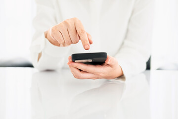 Woman with a finger on the screen using a mobile phone in the office