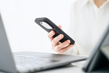 Side view shot of woman's hands using smart phone in interior, rear view of business man hands busy using cell phone at office desk, female officer typing on phone sitting at white table, flare