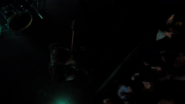 Jib shot of a rock band playing the gig during concert on stage of a large venue, surrounded by bright flashing stage lights