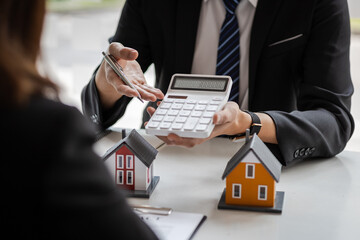 Businessman, real estate agent holding a calculator, presenting a price quote to a client for a house, mortgage, lease, rent, interest, fee, loan, interest. - obrazy, fototapety, plakaty