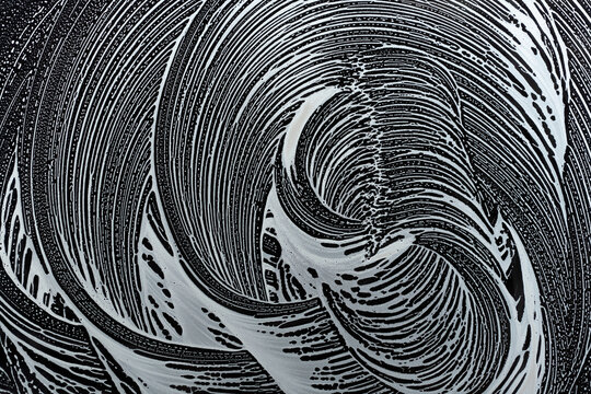 soap foam circles swirl on window glass, window cleaning in spring, black and white