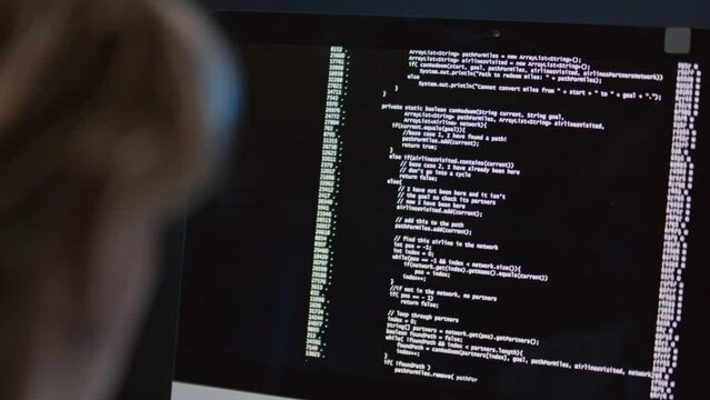 Close up of unrecognizable female programmer sitting at desk looking at computer screen observing code testing process