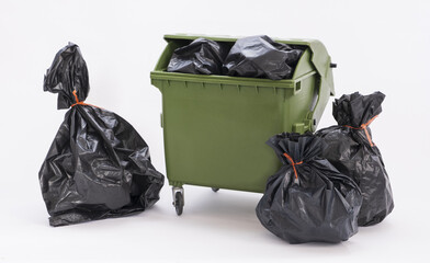 A green dust bin full of rubbish sacks