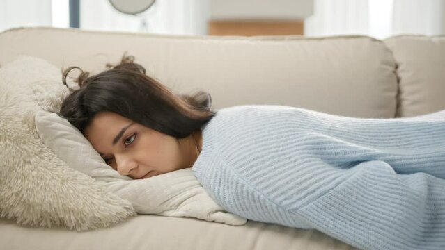 Apathetic bored lady sleeping on couch at home alone. Depression concept. Tired latin girl lying asleep feeling out of energy motivation. Exhausted tired lazy young mixed race woman falls down on sofa