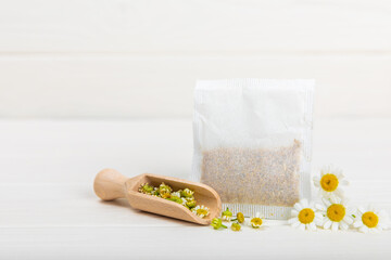 A bag of chamomile tea. Herbal chamomile tea in a bag on a white wooden background. Close-up. Copy...