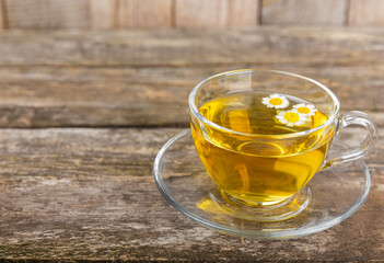 Chamomile herbal tea in a glass cup on a brown wooden table with honey, lemon and chamomile bouquet. Close-up. Copy space. healthy herbal drinks, immunity tea. Natural healer concept.Place for text.