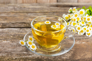 Chamomile herbal tea in a glass cup on a brown wooden table with honey, lemon and chamomile bouquet. Close-up. Copy space. healthy herbal drinks, immunity tea. Natural healer concept.Place for text.