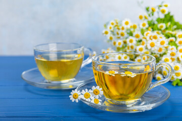 Chamomile herbal tea in a cup on a blue wooden table with honey, lemon and chamomile bouquet. Close-up. Copy space. healthy herbal drinks, immunity tea. Natural healer concept.Place for text.