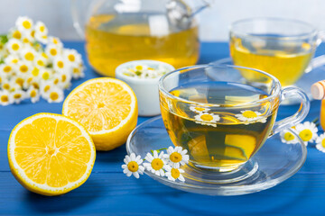Chamomile herbal tea in a cup on a blue wooden table with honey, lemon and chamomile bouquet. Close-up. Copy space. healthy herbal drinks, immunity tea. Natural healer concept.Place for text.