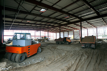 Fototapeta na wymiar Construction site of a hangar building, an excavator and dump trucks loaded
