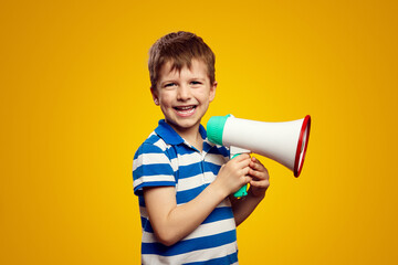 Cheerful little kid wearing blue striped shirt, scream in megaphone announces discounts sale Hurry...