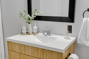 Obraz na płótnie Canvas Modern Scandinavian Bathroom Vanity with White Counter and Black Wooden Mirror with Sustainable Light Wood Cabinets 