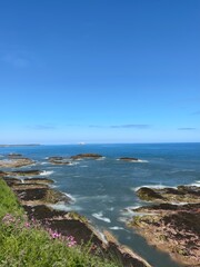 Fototapeta na wymiar Ocean view with waves crashing onto rocks and a clear blue sky background. Dunbar Scotland. 