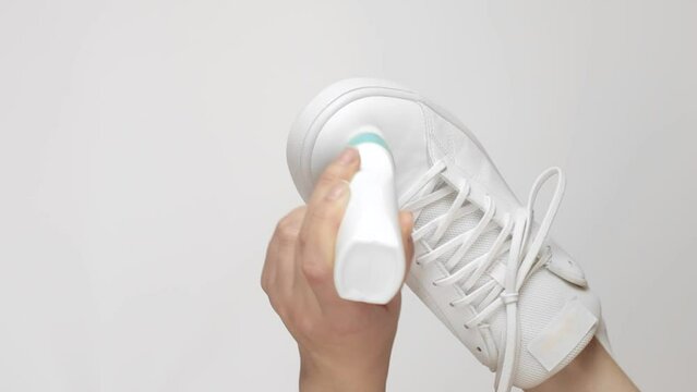 female hands apply cream paint to sneakers. Leather shoe care