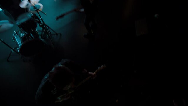 Jib shot of a rock band playing the gig during concert on stage of a large venue, surrounded by bright flashing stage lights