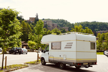 White motorhome parked in Rupit, Osona. Stone houses on top of the green mountain. Family trip to...