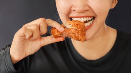 Cheerful people holding fried chicken standing over dark background with copy space.