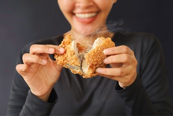 Cheerful people holding fried chicken standing over dark background with copy space. © Mallika