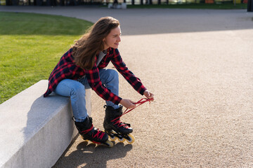 Blonde young caucasian woman putting on the rollerblade inline skates tying laces while sitting on...